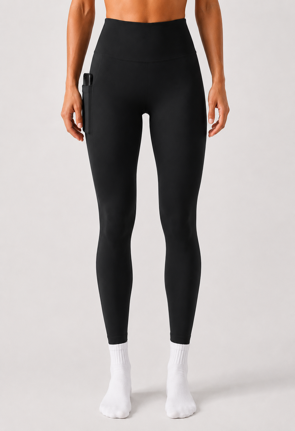 Person wearing black leggings and white socks on a plain background