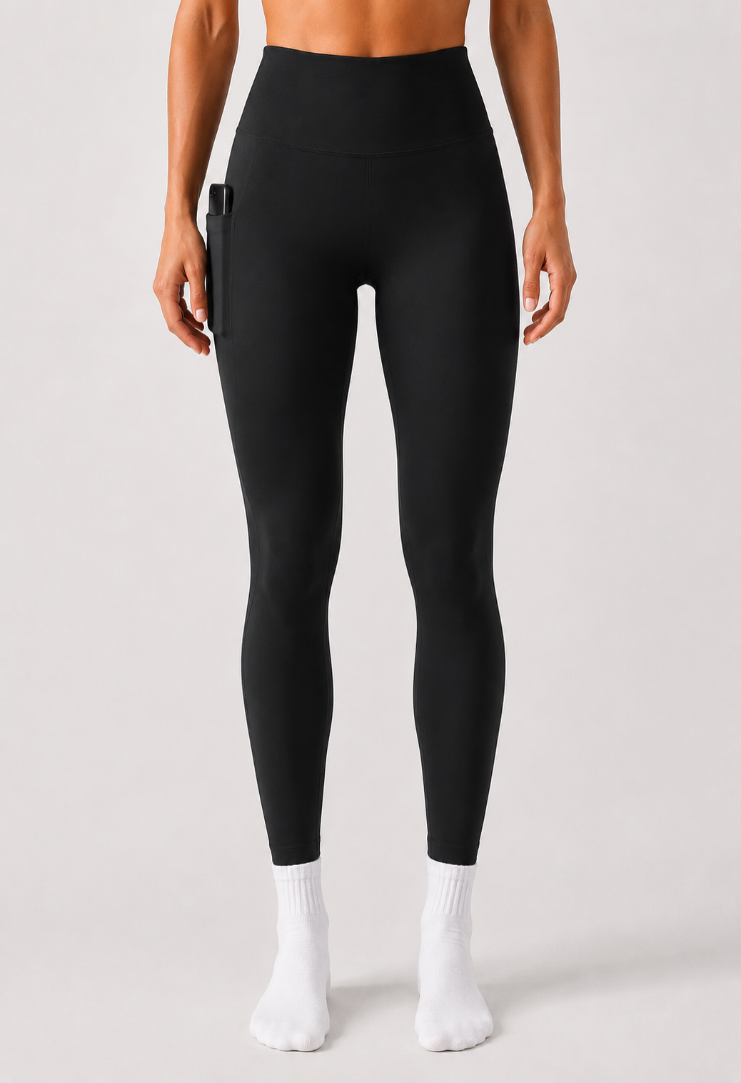 Person wearing black leggings and white socks on a plain background